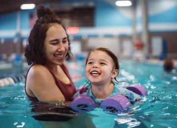 A mum and her toddler child in a swimming pool